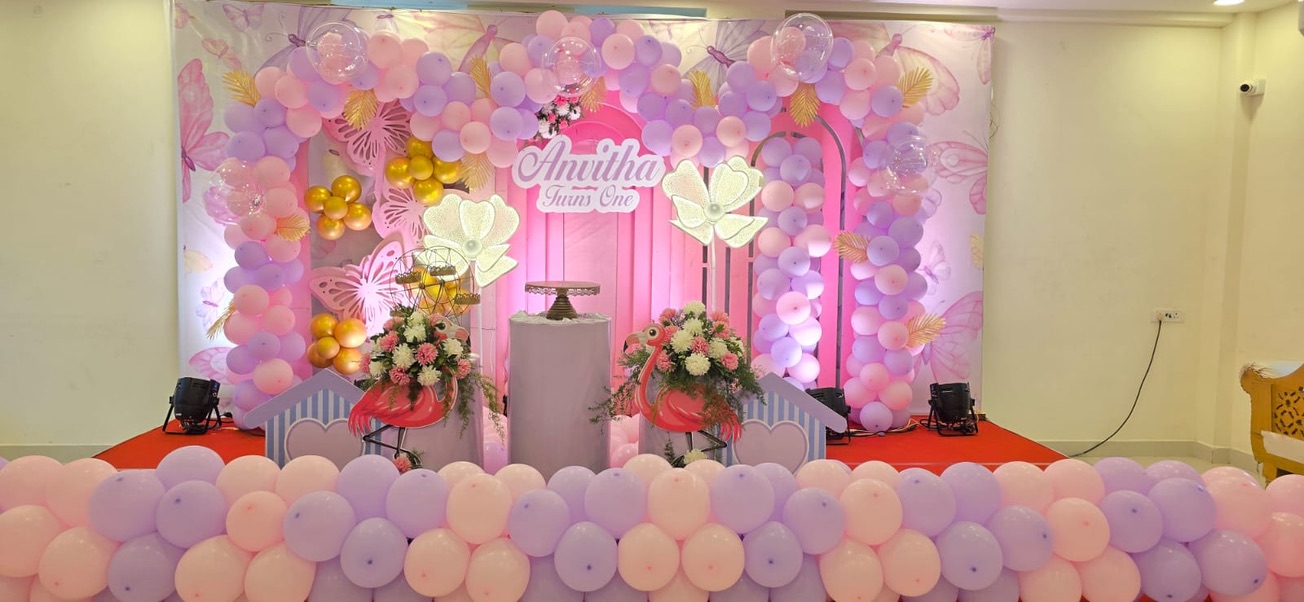 First birthday stage with pink and lilac balloon arch and butterfly decor at VJK Mahal, Pallavaram Chennai