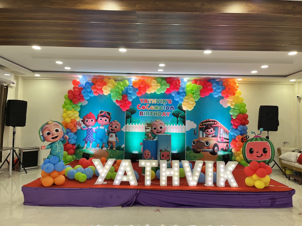 Cocomelon themed kids birthday stage with rainbow balloon arch and marquee letters at VJK Mahal, Pallavaram Chennai