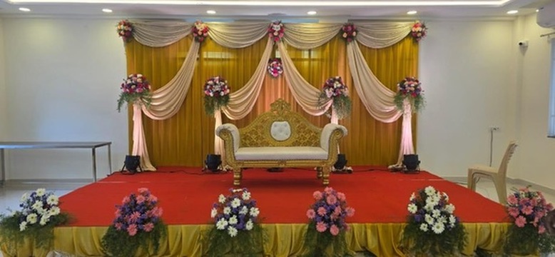 Engagement stage with gold and cream drapes and flower stands at VJK Mahal, Pallavaram Chennai