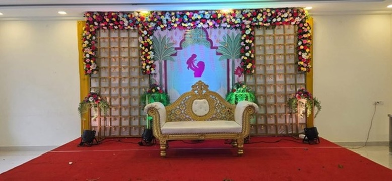 Seemantham stage with mother-and-baby backdrop, flower frame and gold sofa at VJK Mahal, Pallavaram Chennai