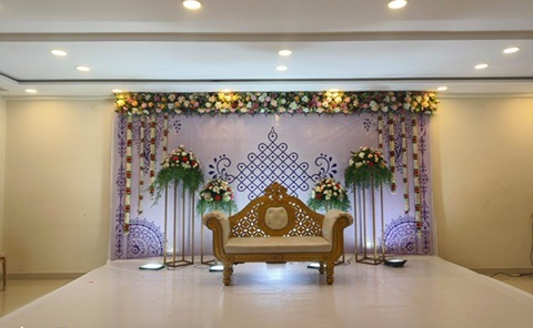 Seemantham stage with kolam-pattern backdrop and flower garlands at VJK Mahal, Pallavaram Chennai